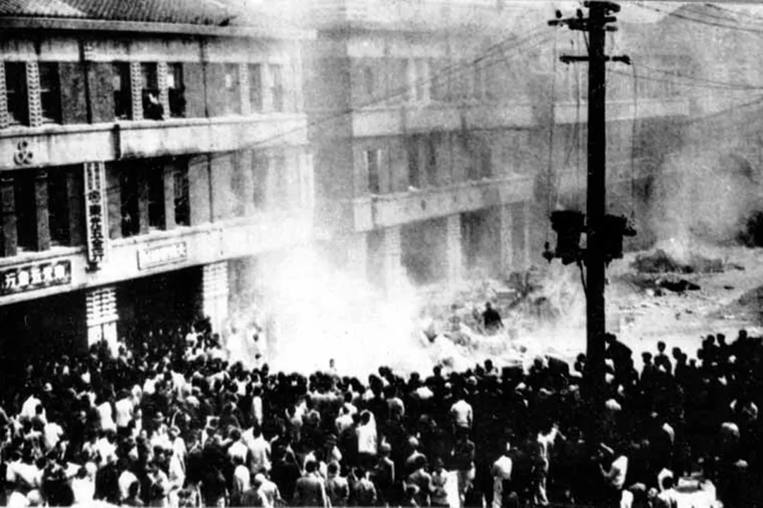 A dense crowd filling the street outside the three-storey Monopoly Bureau building in Taipei, white smoke rising among them